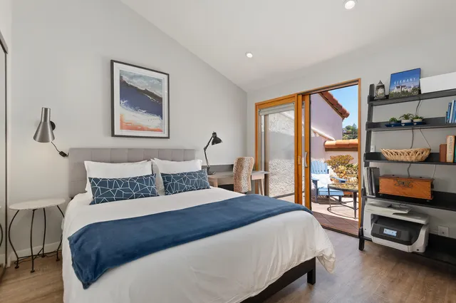 a bedroom with a bed a dresser and a large window