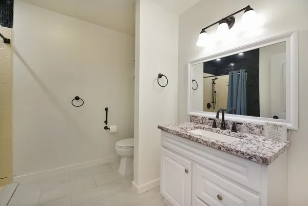 a bathroom with a granite countertop sink a toilet and a mirror