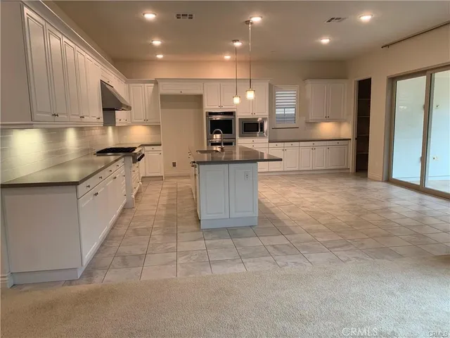 a kitchen with kitchen island granite countertop a stove sink and cabinets