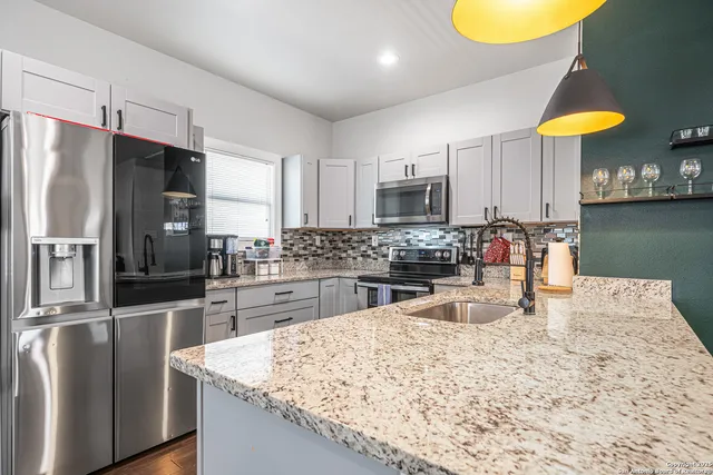 a kitchen with stainless steel appliances granite countertop a sink a stove and refrigerator