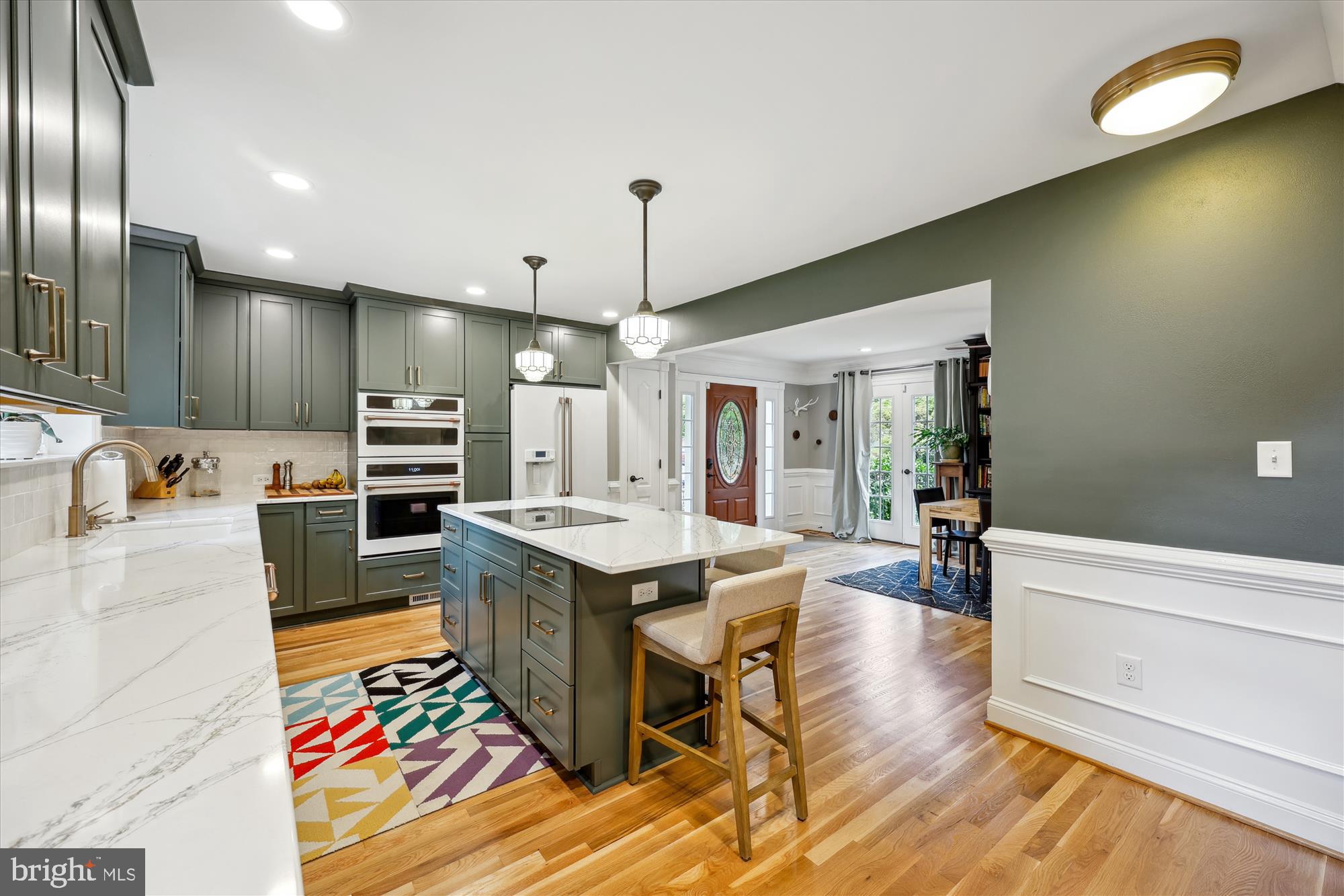 8103 Piney Branch Road Silver Spring, MD 20910 - Photo 7 of 42 a large kitchen with stainless steel appliances kitchen island granite countertop a sink dishwasher a stove and a dining table with wooden floor