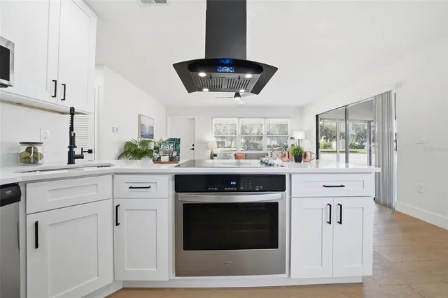a kitchen with stainless steel appliances white cabinets and a stove top oven