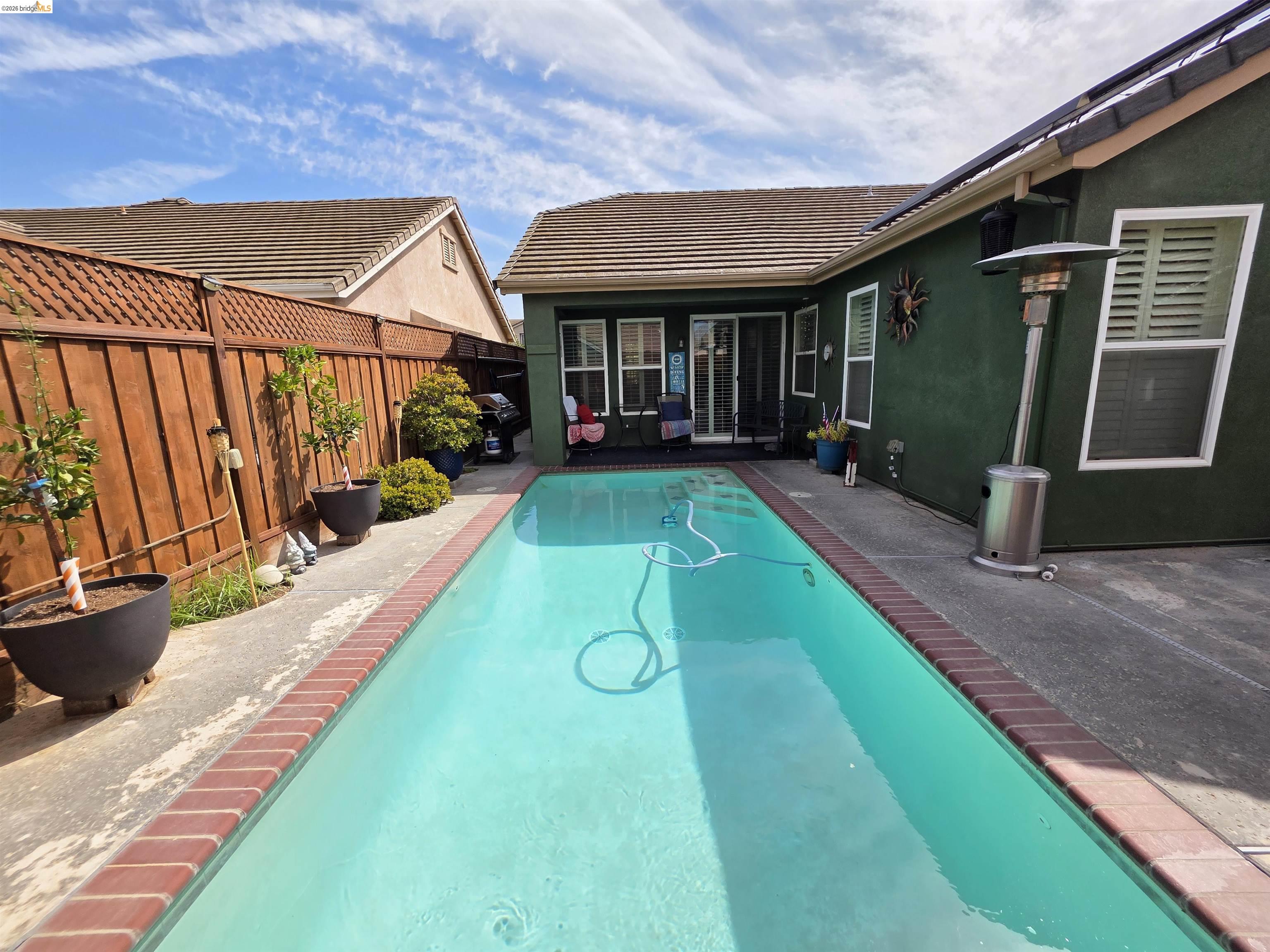 2607 Glow Road Riverbank, CA 95367 - Photo 37 of 42 Rectangular swimming pool with brick coping, concrete surround, and a wooden privacy fence