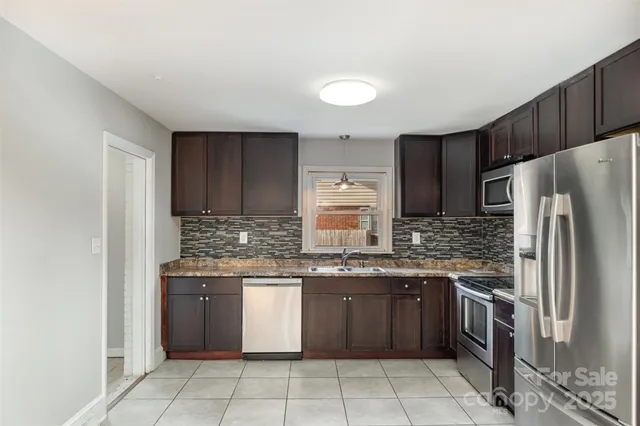 a kitchen with stainless steel appliances granite countertop a stove top oven a refrigerator and a sink