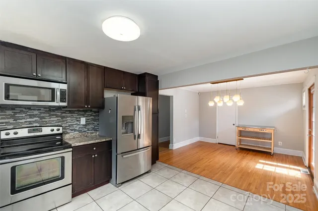 a kitchen with stainless steel appliances granite countertop a refrigerator a stove a sink and a microwave