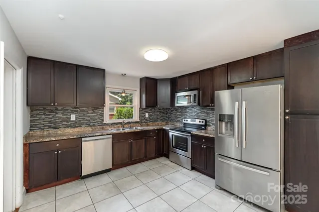 a kitchen with stainless steel appliances granite countertop a refrigerator and a sink