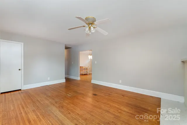 a view of empty room with wooden floor and ceiling fan