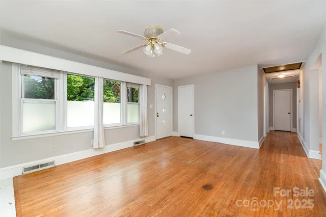a view of an empty room with wooden floor and a window