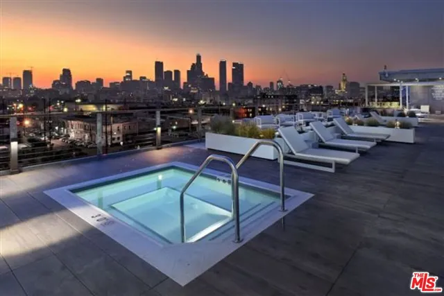a view of roof deck with table and chairs a barbeque with wooden floor and fence