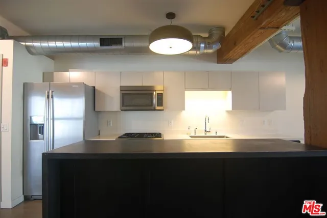 a kitchen with stainless steel appliances granite countertop a refrigerator a sink dishwasher a stove and a refrigerator with wooden floor