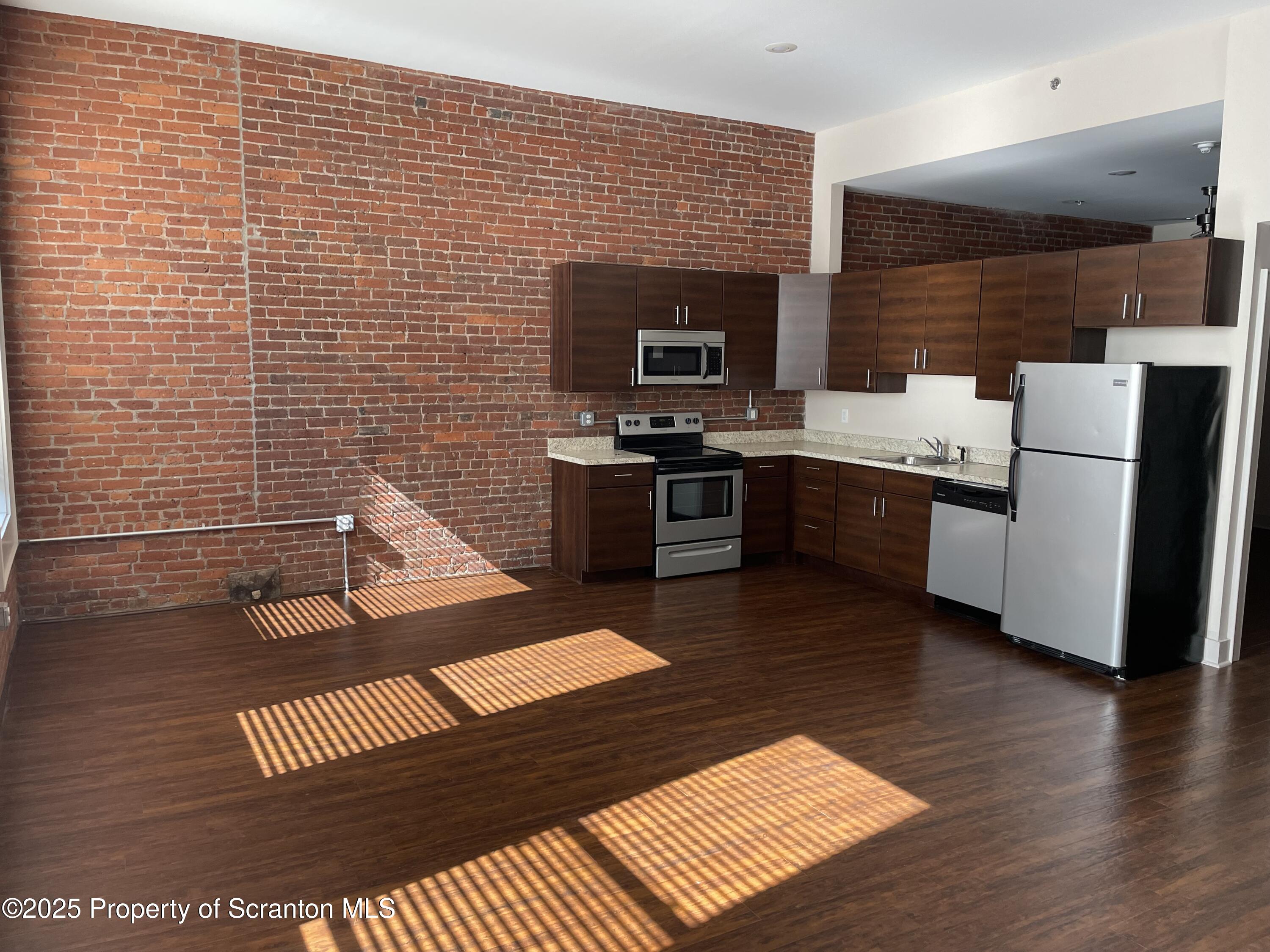 a view of kitchen with stainless steel appliances wooden floor and living room view