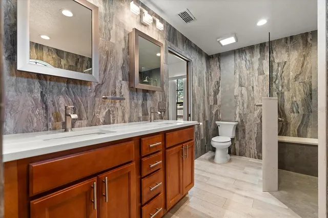 a spacious bathroom with a double vanity sink a toilet and a mirror