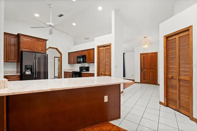 a large kitchen with stainless steel appliances a large counter top a refrigerator and a sink