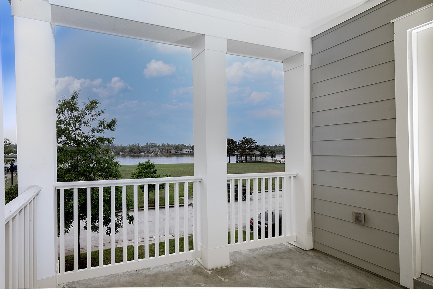 190 West Breezy Way Spring, TX 77380 - Photo 13 of 33 The balcony with a crisp, white railing offers a serene view of a lake and green landscape, perfect for relaxation.