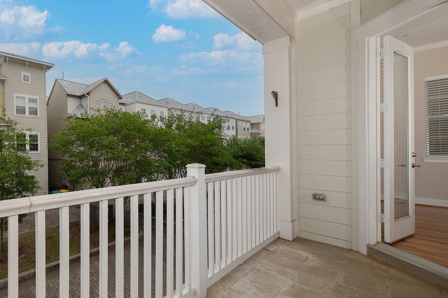 190 West Breezy Way Spring, TX 77380 - Photo 21 of 33 This photo features a cozy balcony with white railings, offering a view of neighboring townhouses and lush greenery.