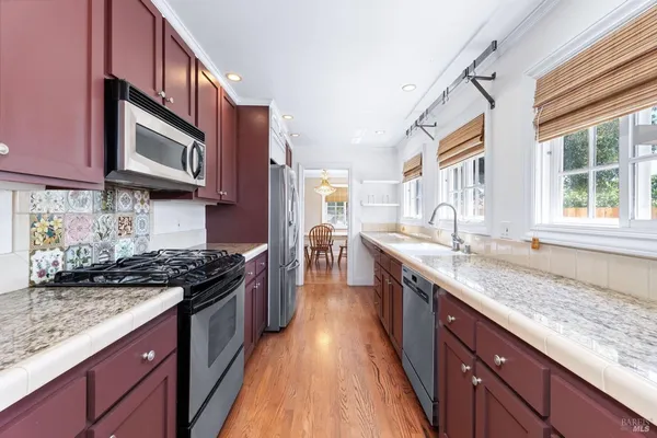 a kitchen with granite countertop stainless steel appliances a stove sink and cabinets