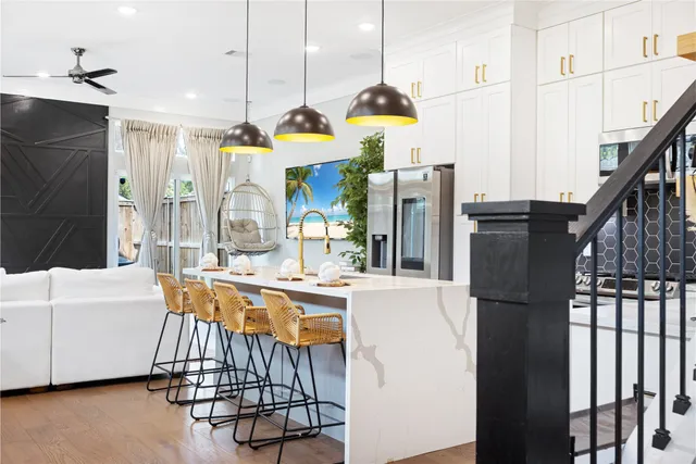 a kitchen with stainless steel appliances kitchen island granite countertop a stove a sink a refrigerator and a dining table with wooden floor