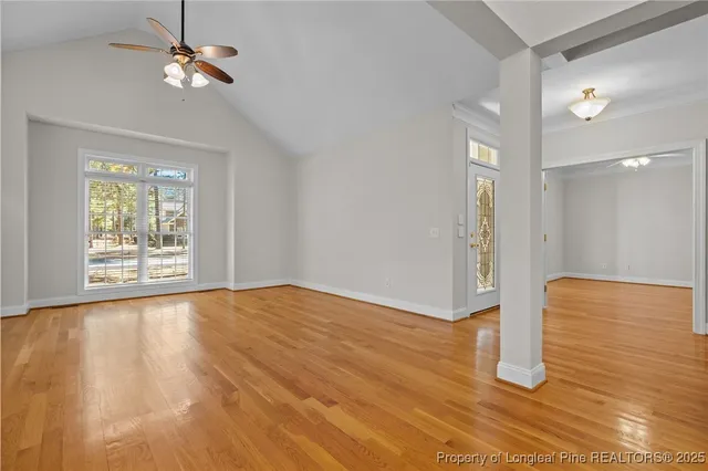 a view of an empty room with wooden floor fireplace and a window