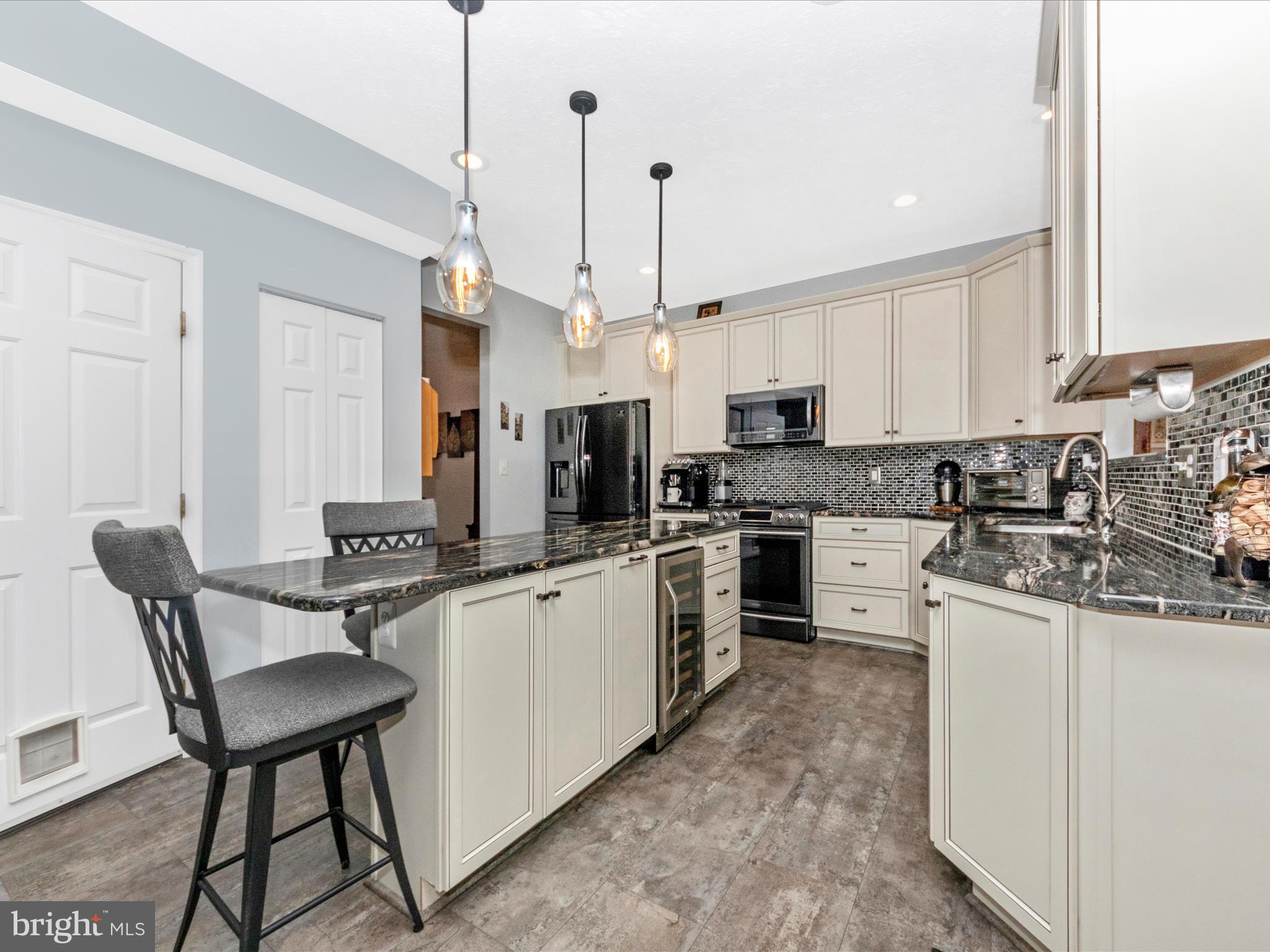 7732 Rotherham Drive Hanover, MD 21076 - Photo 6 of 55 a kitchen with stainless steel appliances kitchen island a table chairs sink and cabinets