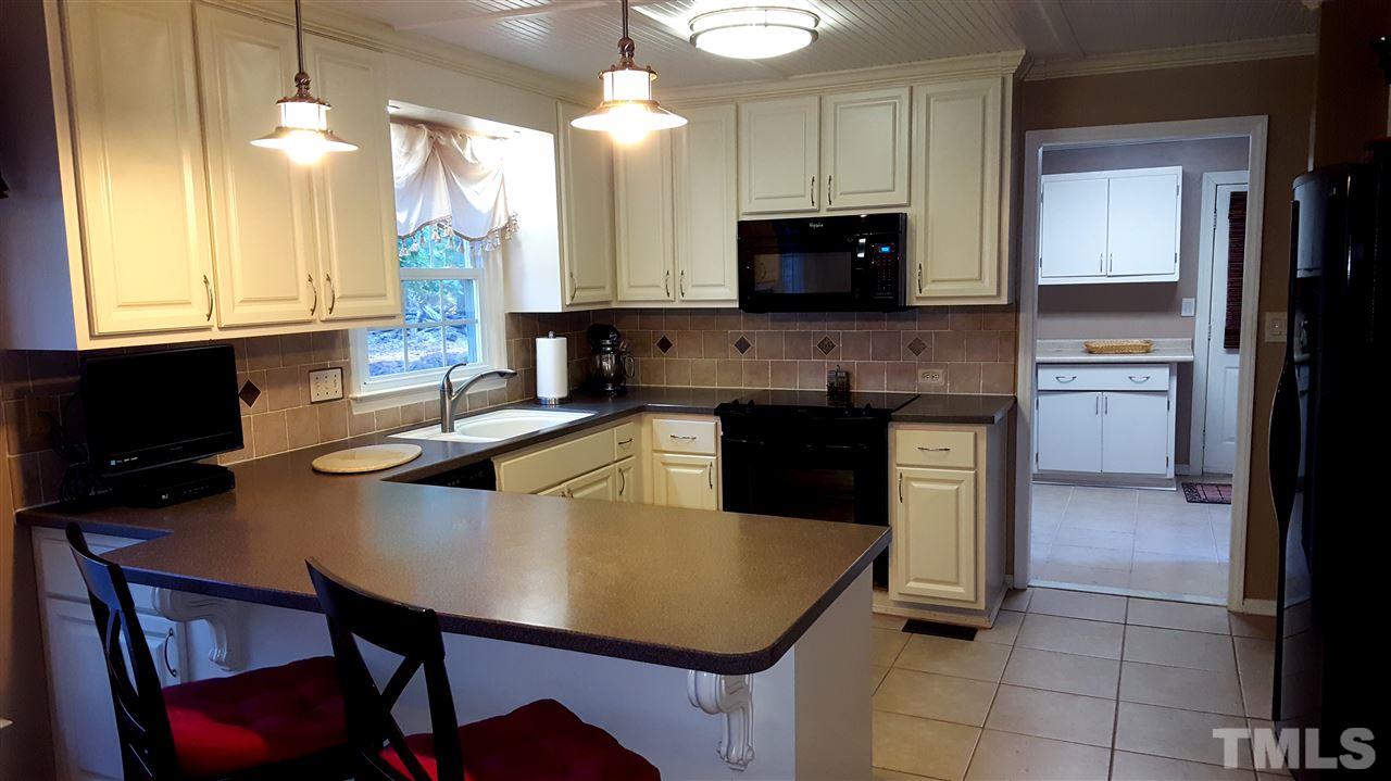 1113 Hamilton Way Durham, NC 27713 - Photo 10 of 25 a kitchen with a stove a sink a microwave a dining table and chairs