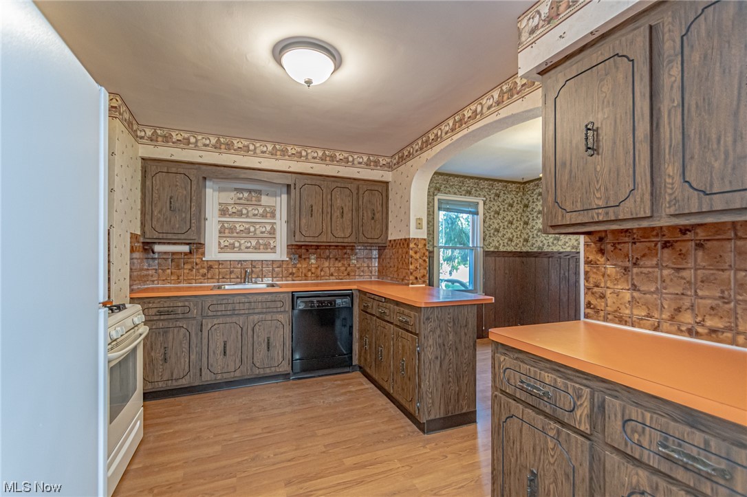 8358 Ridge Road North Royalton, OH 44133 - Photo 13 of 25 Kitchen featuring backsplash, light countertops, light hardwood floors, black dishwasher, and white gas range