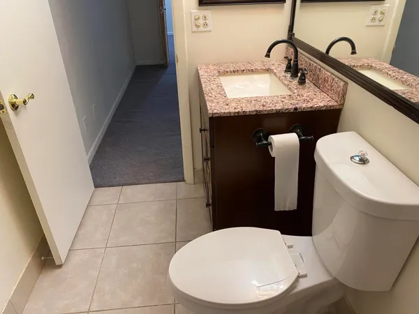 a bathroom with a granite countertop sink toilet and a mirror