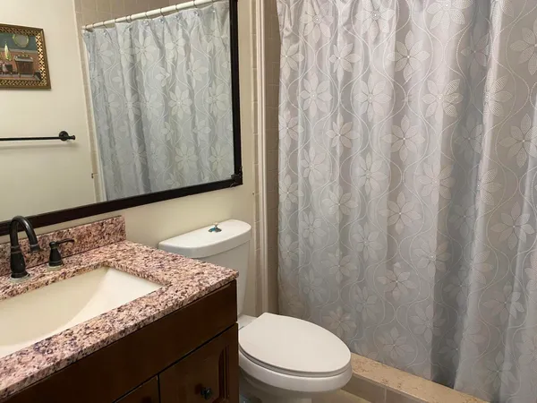 a bathroom with a granite countertop sink toilet and shower