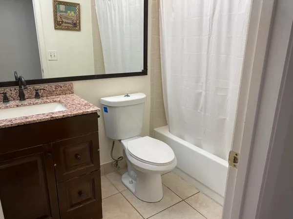 a bathroom with a granite countertop sink toilet and mirror