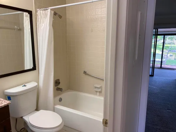 a view of a hallway with wooden floor and a bathroom