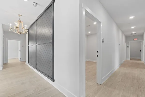 a view of a hallway with wooden floor and chandelier