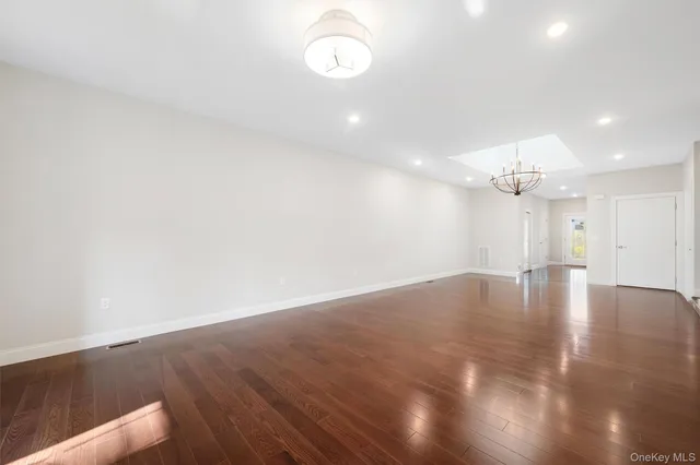 a view of an empty room with wooden floor and staircase