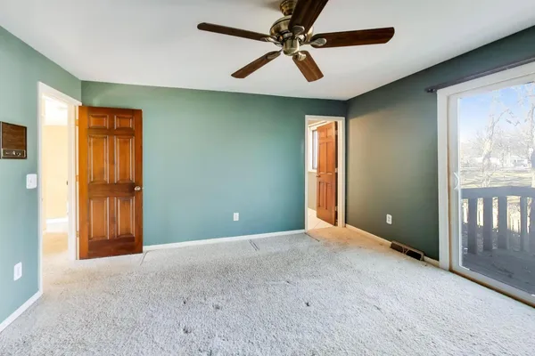 an empty room with windows and fan