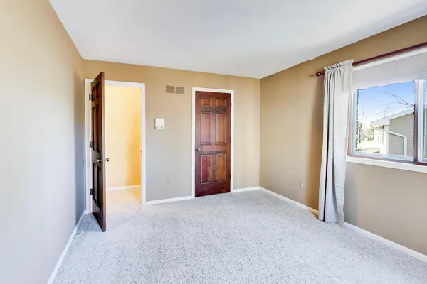 a view of an empty room with window and closet area