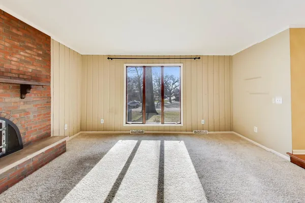 a view of an empty room with a fireplace and a window