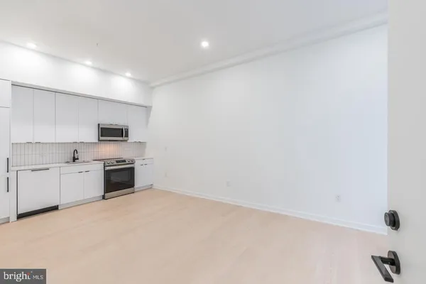 a large kitchen with white cabinets and stainless steel appliances