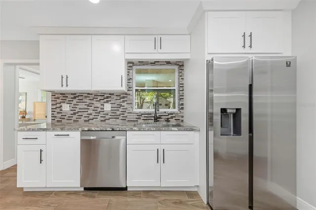 a kitchen with white cabinets and refrigerator