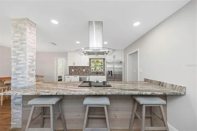 a kitchen with granite countertop a table chairs in it and wooden floors