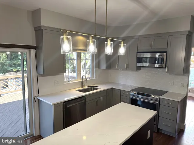 a kitchen with stainless steel appliances kitchen island granite countertop a sink a stove and a wooden floors