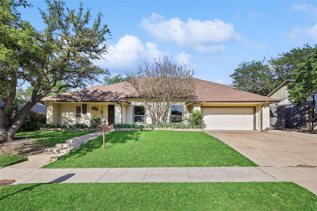 a view of a white house next to a yard with big trees