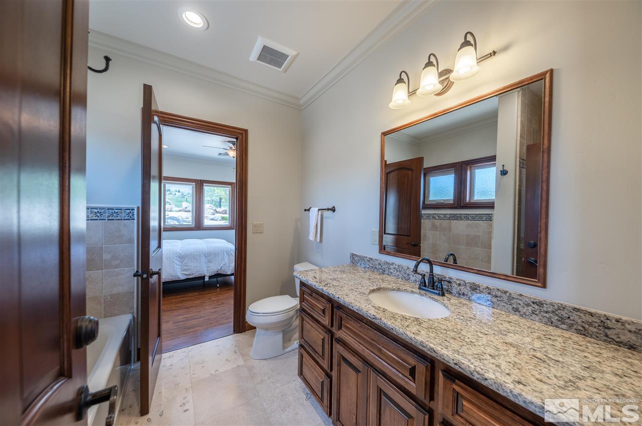 12835 Silver Wolf Road Reno, NV 89511 - Photo 14 of 31 a en suite bathroom with a granite countertop sink and a mirror
