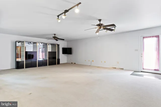 an empty room with chandelier fan and windows