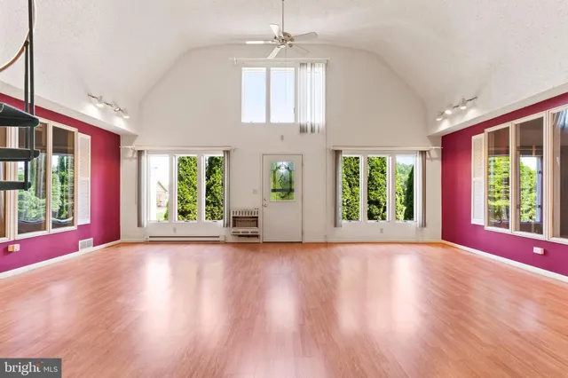 an empty room with wooden floor and windows