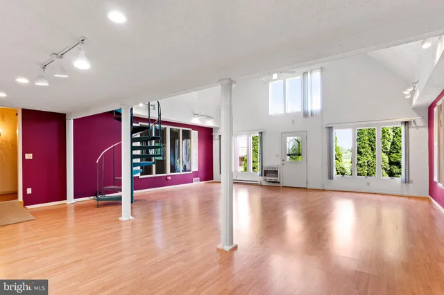 a view of an empty room with window and wooden floor