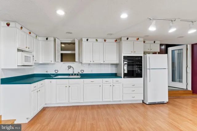 a kitchen with granite countertop white cabinets and refrigerator