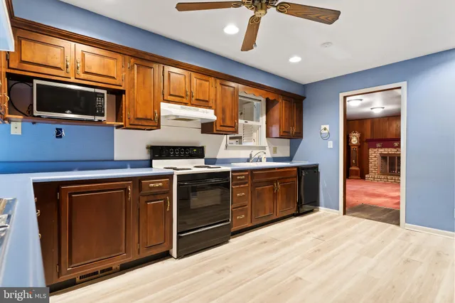 a kitchen with stainless steel appliances granite countertop a stove top oven a sink dishwasher a dining table and chairs with wooden floor