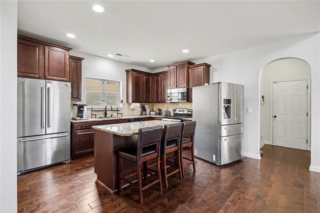 767 Effendi Place Fairburn, GA 30213 - Photo 12 of 35 a kitchen with stainless steel appliances granite countertop a refrigerator a stove a sink dishwasher and a refrigerator with wooden floor