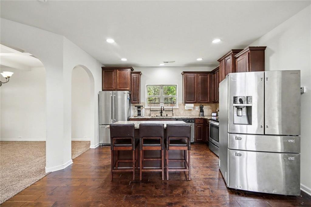 767 Effendi Place Fairburn, GA 30213 - Photo 13 of 35 a kitchen with stainless steel appliances granite countertop a refrigerator a stove a sink a dining table and chairs with wooden floor