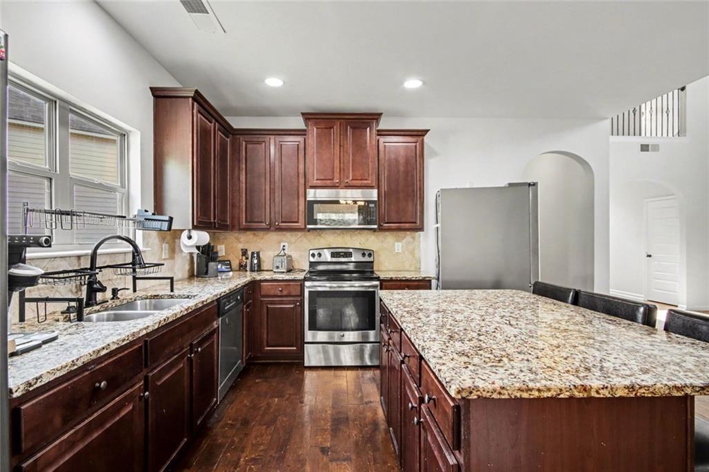 767 Effendi Place Fairburn, GA 30213 - Photo 14 of 35 a kitchen with kitchen island granite countertop a sink stove refrigerator and cabinets