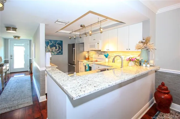 a view of a kitchen with kitchen island a sink a counter space and wooden floor