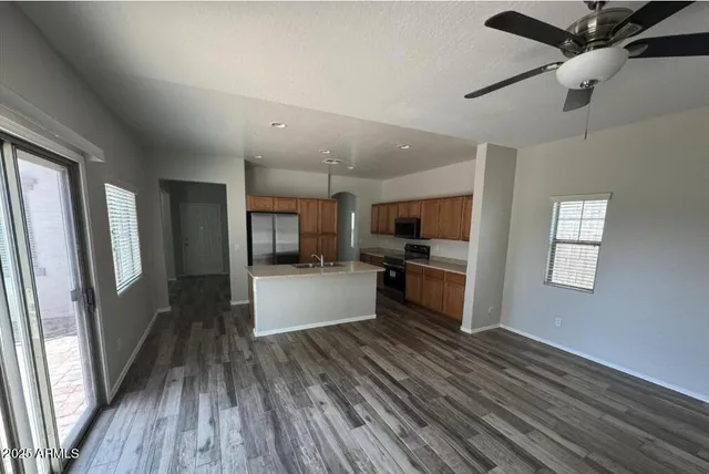 a kitchen with stainless steel appliances kitchen island granite countertop a refrigerator a sink a stove and white cabinets with wooden floor